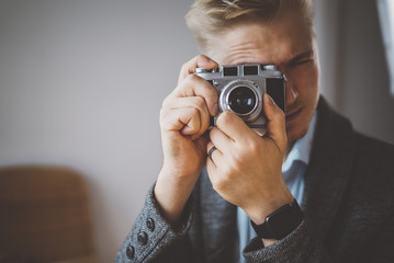Close-up of young male photographer taking photo on vintage film camera at modern photo-studio, artist concept, shooting-photography, creative