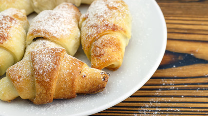 Homemade fresh bagels in white plate on wooden background.