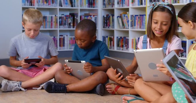 Slow motion of school kids using digital tablet in library 4k