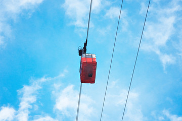 Beautiful old red aerial funiculair train cabine moving across, isolated on bright blue sky