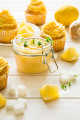 Preparing lemon cupcakes with citrus curd on white wooden background. Selective focus