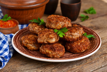 Homemade meatballs with meat and onions on a wooden background.
