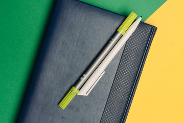 two pens lie on a notepad and a colorful background