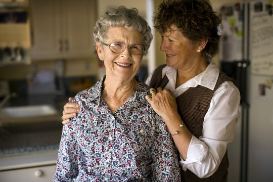 Smiling mature woman gives her elderly mother an affectionate squeeze.