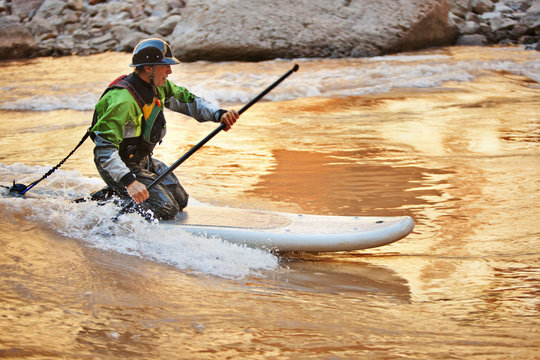 Mid adult man paddleboarding on a river.