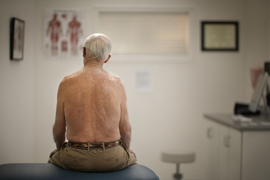 Rear view of senior man sitting in clinic