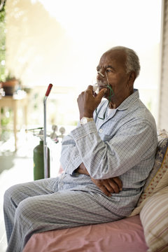 Unwell elderly man uses oxygen mask.