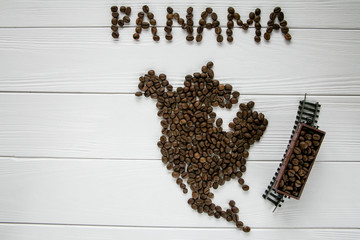 Map of the Panama made of roasted coffee beans laying on white wooden textured background with toy train. Space for text