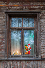 Old wooden window in dwelling decorated with candles, Santa and deer pictures. Meeting holiday.