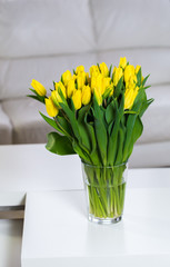 Bouquet of yellow tulips in a glass vase at home