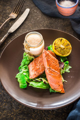 Baked salmon with green and lemon on ceramic plate