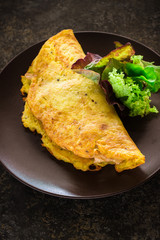 Omelet and green salad on ceramic plate.
