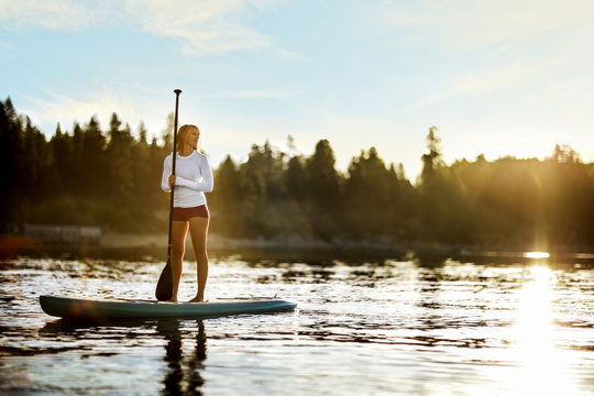 Young woman paddle boarding on a lake.