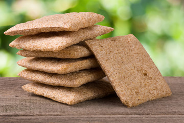 stack of crisp bread on a wooden table with blurred garden background