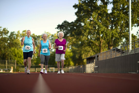 Happy Senior Women Walking On An Athletic Track.
