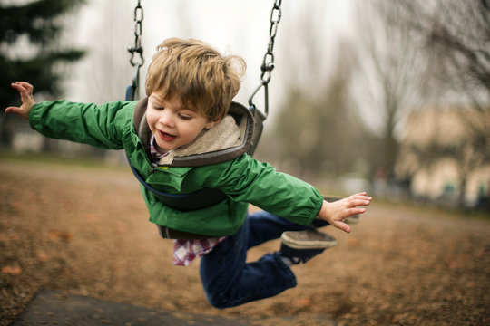 Boy playing on chain swing at park