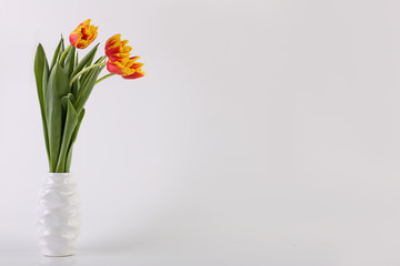 Fototapeta na wymiar Postcard - a bouquet of yellow-red tulips in a vase. Holidays: Valentine's Day, 8 March, Easter.