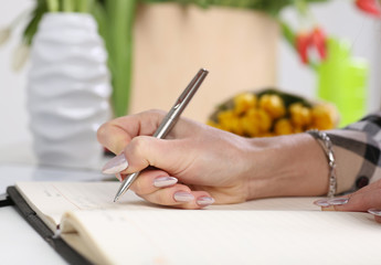 Woman takes notes in a diary. Against the background of tulips.The image depth of field