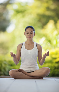 Relaxed young woman meditating on a deck.