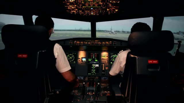 Cabin crew in the cockpit or flight deck of a passenger airplane use radio to talk with air traffic controller before taxiing on the runway and departure on Airbus A319 A320 A321. Ready to take off