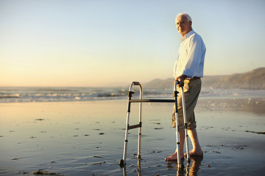 Senior man standing on beach with walker