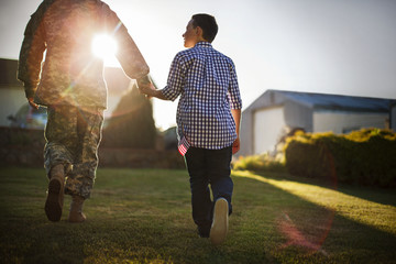 Mid adult man dressed in a military uniform is greeted by his son.