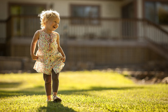 Young girl skipping across a back yard.
