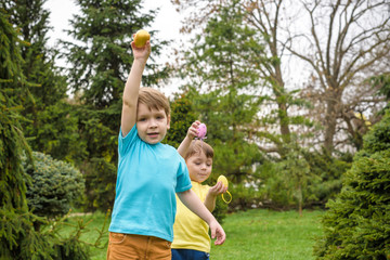 Obraz premium Kids on Easter egg hunt in blooming spring garden. Children sear