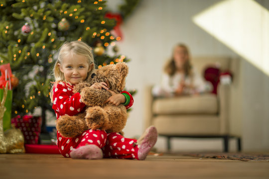 Portrait of a young girl hugging her teddy bear on Christmas morning.