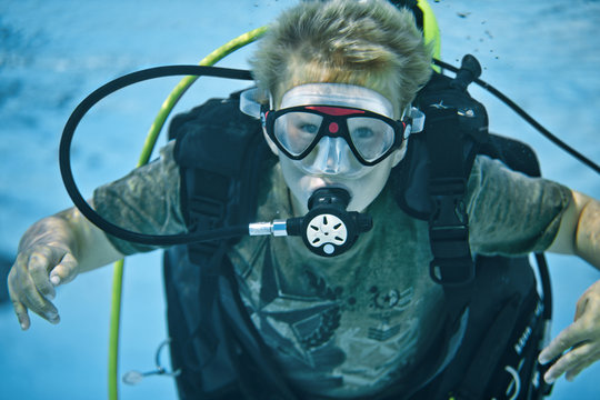Young boy learning how to scuba dive in a pool.