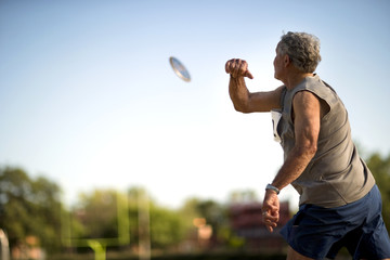 Mature man throwing a discus during an athletics event.