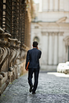 Young businessman makes a call as he strolls along a city street.