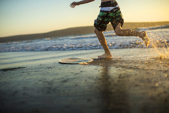 Teenage boy surfing at sunset.