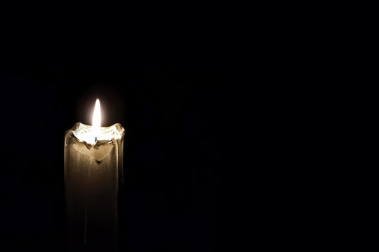 Mourning Glowing Candle on black background.Empty space for text.