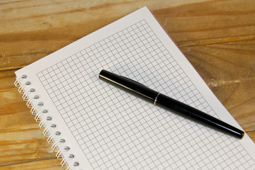 Notebook with the fountain pen on a wooden desk