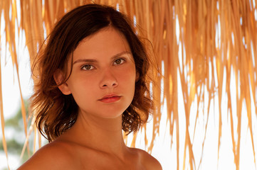 Close up portrait of teen brunette under straw umbrella © Vitya