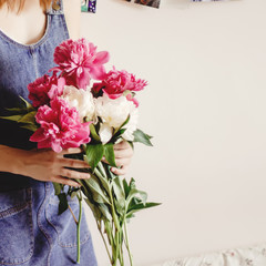 woman hipster in denim dress holding peony bouquet in the mornin