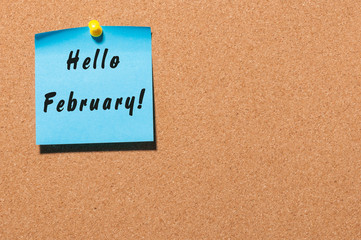 hello February on sticker pinned on cork notice board with empty space for text