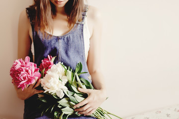 woman hipster in denim dress holding peony bouquet in the mornin