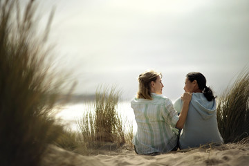 Two friends having a heart-to-heart talk while sitting on the beach.
