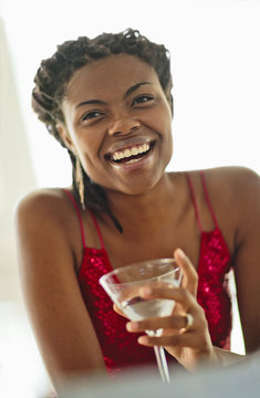Smiling young woman enjoying a cocktail at a bar.