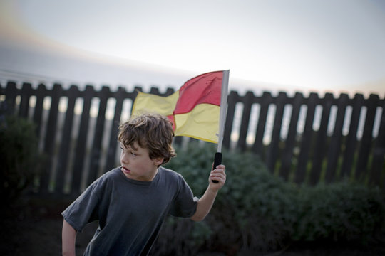 Boy carrying a lifeguard flag.