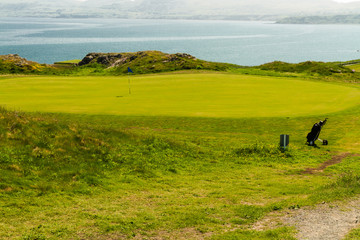 Fototapeta na wymiar Golf course putting green sea in background and golf bag.