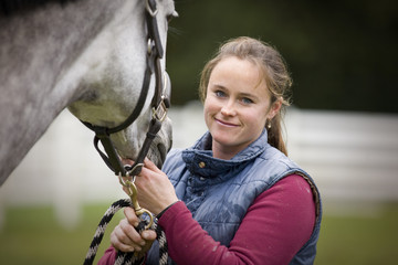 Portrait of a young woman standing with her horse
