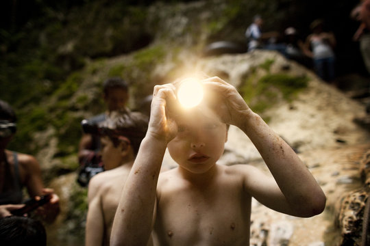 Portrait of young boy wearing a headlamp during an outdoor adventure.