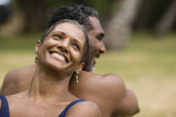 Couple sitting back to back and smiling.