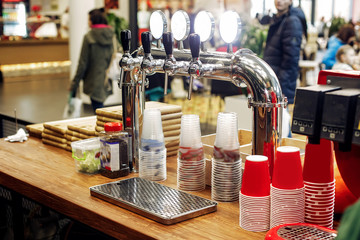 beer bar with stylish taps and plastic cups  on wooden desk. cat