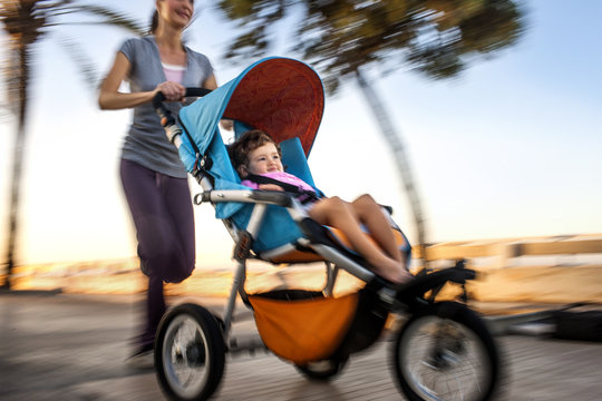 Woman jogging while pushing her daughter in a stroller.