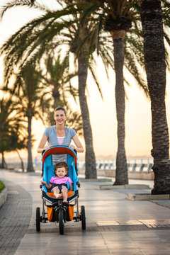 Mother pushing her daughter in a stroller along the waterfront.