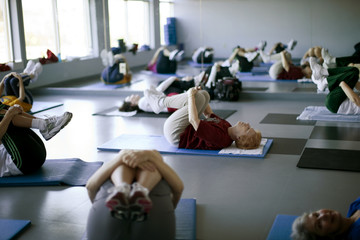 Elderly exercise class stretches on mat.